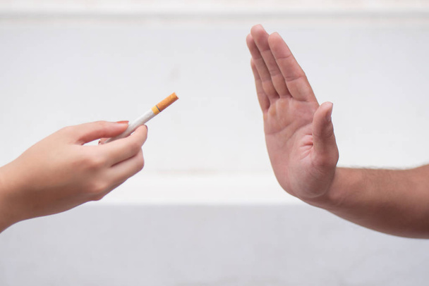 man hand probeert te stoppen met roken door het afwijzen van sigarettenaanbod, nee zeggen tegen sigarettenrook; concept van stoppen met roken, rookverbod of niet roken hier - Foto, afbeelding