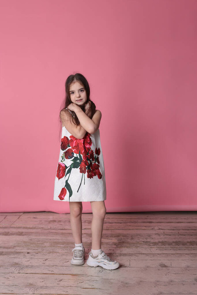 fille souriante de huit ans dans une belle robe sur un fond rose joyeuse humeur de printemps
 - Photo, image