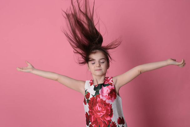 χαμογελαστό κορίτσι οκτώ ετών σε ένα όμορφο φόρεμα σε ροζ φόντο χαρούμενη ανοιξιάτικη διάθεση - Φωτογραφία, εικόνα