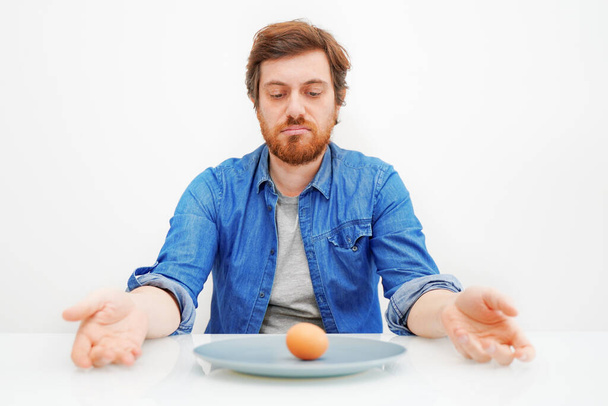 Сумний голодний чоловік їсть овочі ізольовані на білому тлі
 - Фото, зображення