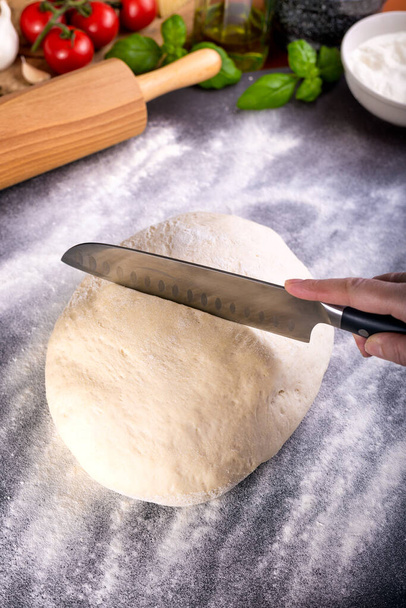 Prepering and cutting pizza dough with knife - Photo, Image