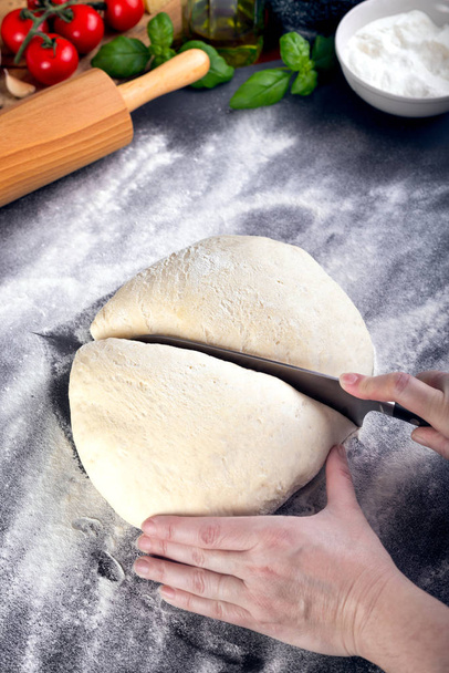 Prepering and cutting pizza dough with knife - Foto, afbeelding