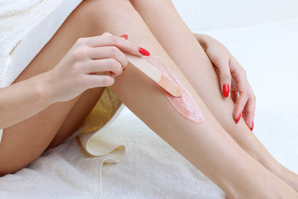 Woman waxing her legs with wooden stick. - Photo, Image