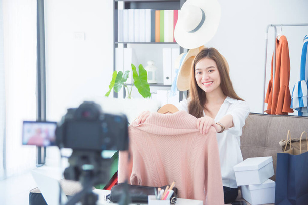 Красива жінка-блогер, що показує одяг перед камерою для запису вхідного відео в прямому ефірі в її магазині
. - Фото, зображення