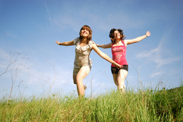 two girls jumping in field - Foto, immagini