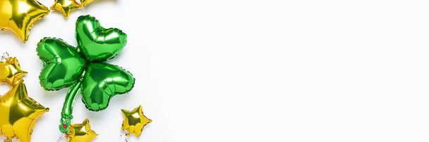 Воздушный шар Клевер и Воздушные Золотые шарики звезды формы на белом фоне. Концепция праздника, вечеринка, Ирландия, День Святого Патрика, удача. Баннер плоский, вид сверху
 - Фото, изображение