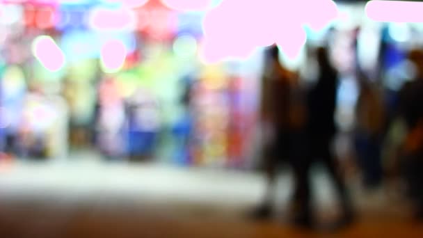 Shadows and silhouettes of people in front of stores at night. Strong back light from stores. Out of focus. Blurred. A lot of movement. - Filmagem, Vídeo