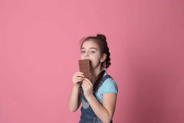 Улыбающаяся счастливая девушка в отличном веселом настроении ест сладкое угощение шоколад на ярко-розовом фоне
 - Фото, изображение