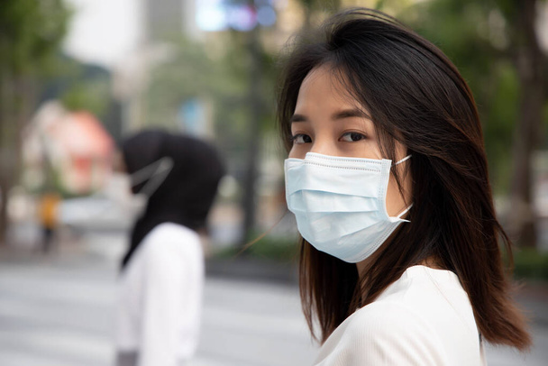汚染されたスモッグやウイルス感染症の流行を持つ都市でマスクを身に着けている病気の女性;バイオハザードの概念,生物学的危険性,予防医療,病気の隔離,コロナウイルス感染症 - 写真・画像