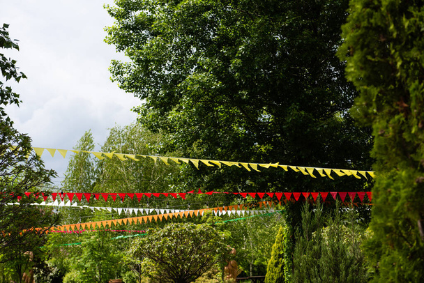 Nombreux drapeaux colorés suspendus décor entre les arbres
 - Photo, image