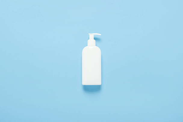 White plastic bottle with dispenser on a blue background. Concept medicine, hygiene, cosmetics, perfumery. Banner. Flat lay, top view - Фото, изображение