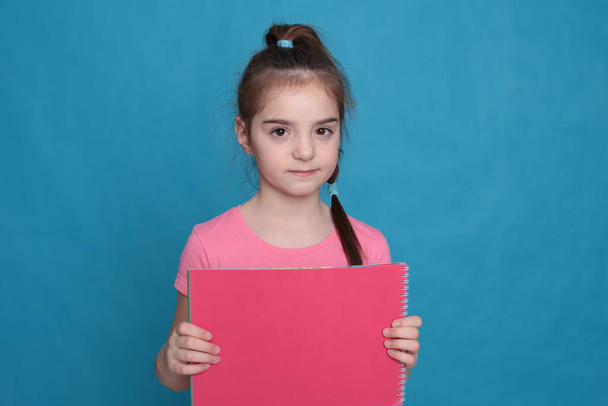 chica divertida de ocho años de edad sostiene una hoja de color de papel espacio libre para escribir sobre un fondo brillante
 - Foto, Imagen