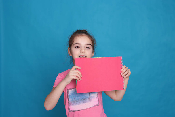 смешная девочка восьми лет держит цветной лист бумаги свободного места для написания на ярком фоне
 - Фото, изображение