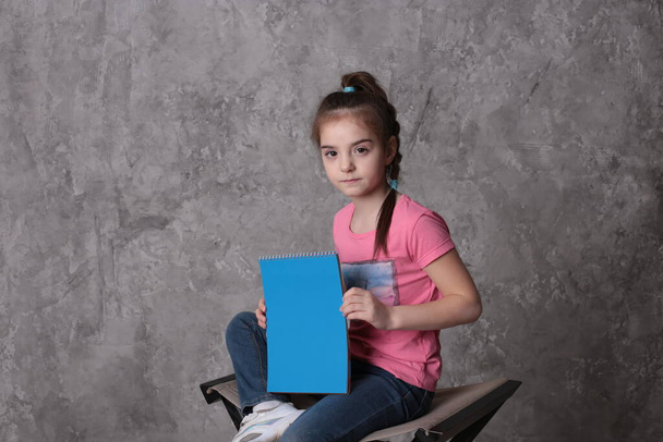 grappig meisje van acht jaar oud houdt een gekleurde vel papier vrije ruimte voor het schrijven op een heldere achtergrond - Foto, afbeelding