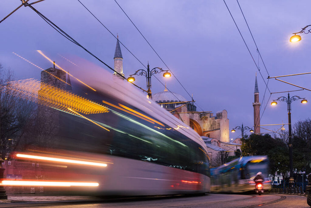 Istanbul, Turkey - Jan 9, 2020: A T1 tram passes the Hagia Sophia museum at dusk, Istanbul, Turkey - Фото, зображення