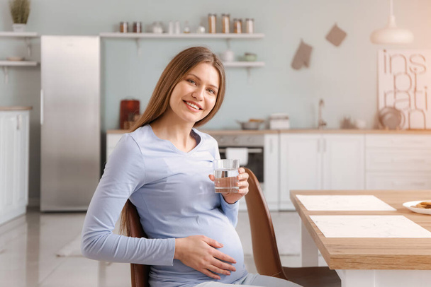 Belle femme enceinte avec verre d'eau dans la cuisine
 - Photo, image