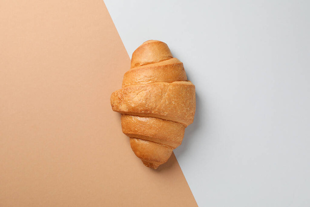 Freshly baked croissant on two tone background, top view - Φωτογραφία, εικόνα