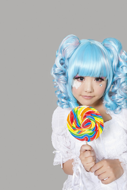 Woman dressed as a doll holding lollipop - Foto, imagen