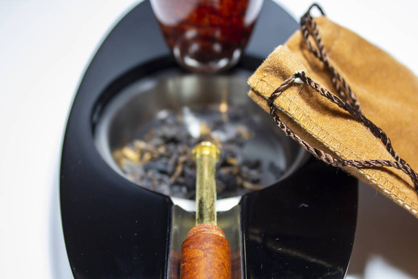 Tobacco pouch leaning against the ashtray with pipe and pipe sto - 写真・画像
