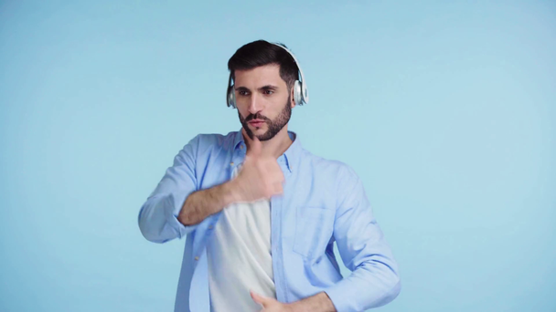 man in headphones dancing isolated on blue  - Footage, Video