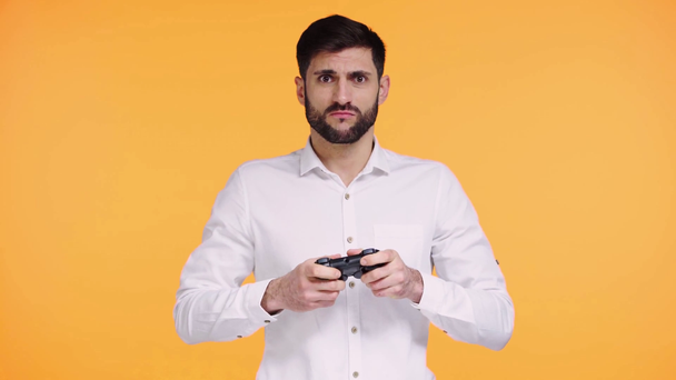 KYIV, UKRAINE - NOVEMBER 21, 2019: upset man playing video game isolated on orange - Video