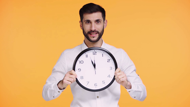 happy man holding clock isolated on orange - Imágenes, Vídeo