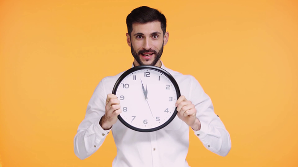 άνθρωπος κρατώντας το ρολόι και χαιρετώντας χέρι απομονώνονται σε πορτοκαλί  - Πλάνα, βίντεο