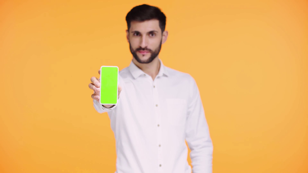 εστίαση έλξης του ανθρώπου κρατώντας smartphone με πράσινη οθόνη απομονώνονται σε πορτοκαλί  - Πλάνα, βίντεο