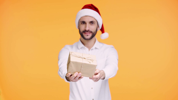 εστίαση έλξη του ανθρώπου στο καπέλο santa με δώρο απομονώνονται σε πορτοκαλί - Πλάνα, βίντεο