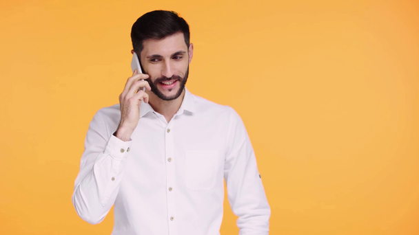 Akıllı telefondan konuşan mutlu adam turuncu renkte izole edilmiş. - Video, Çekim