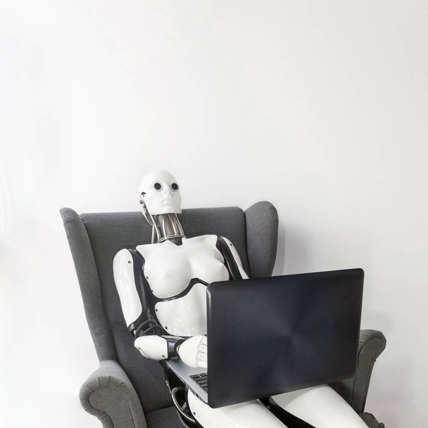 Robot pracujący z laptopem siedząc w fotelu - Zdjęcie, obraz