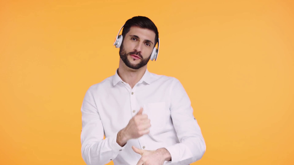 glücklicher Mann mit Kopfhörern, der isoliert auf Orange tanzt   - Filmmaterial, Video