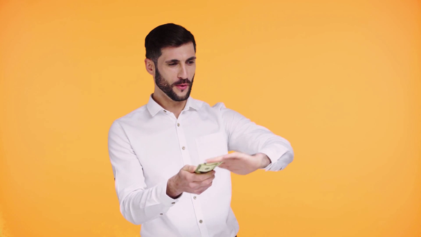 człowiek rzucając pieniądze w powietrzu odizolowany na pomarańczowy  - Materiał filmowy, wideo