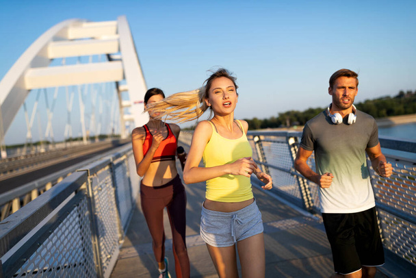 フィットネス、スポーツ、人とジョギングの概念。屋外で走る幸せな人々 - 写真・画像