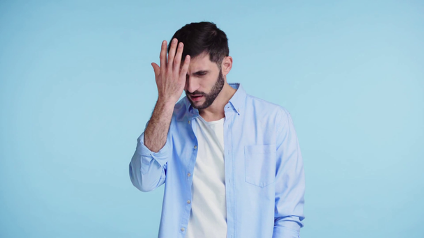 frustrado hombre tocando la cara aislado en azul
 - Imágenes, Vídeo