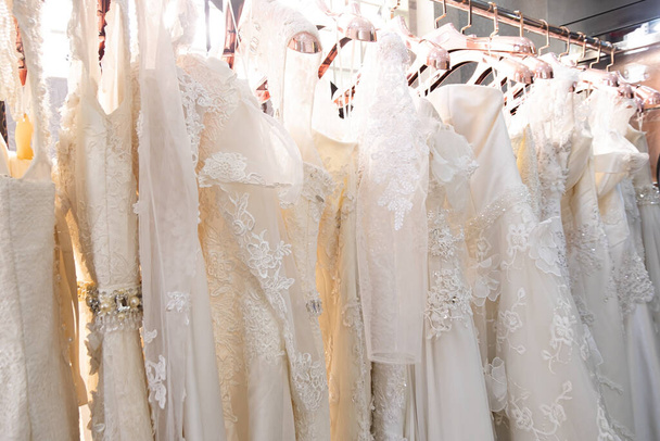 Beautiful, White bridal dress texture on background. Wedding dresses hanging on a hanger interior of bridal salon. Design, fashion modern luxury in detail. - Foto, Imagem
