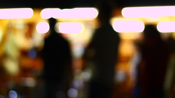 Shadows and silhouettes of people in front of stores at night. Strong back light from stores. Out of focus. Blurred. A lot of movement. - Filmmaterial, Video
