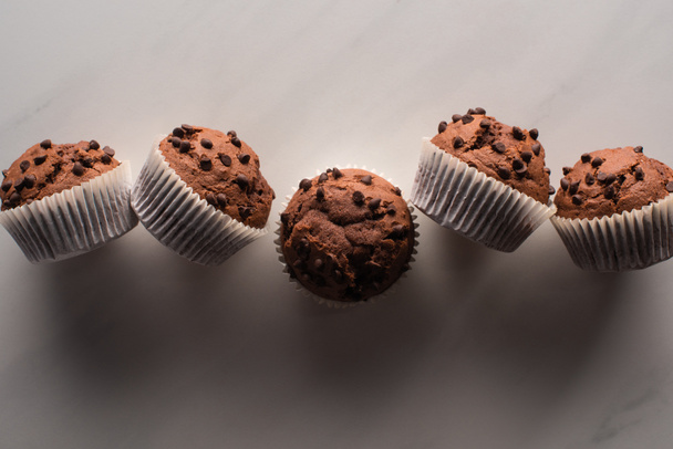 top view of fresh chocolate muffins on marble surface - Φωτογραφία, εικόνα