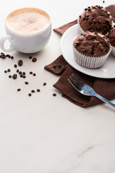 fresh chocolate muffins on white plate near fork and coffee - 写真・画像