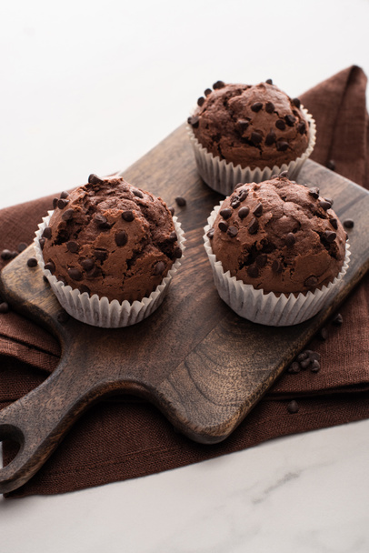 fresh chocolate muffins on wooden cutting board on brown napkin - 写真・画像