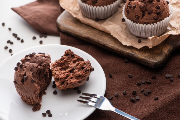 fresh chocolate muffins on wooden cutting board and plate with fork - Foto, immagini