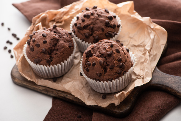 fresh chocolate muffins on wooden cutting board on brown napkin - Fotó, kép