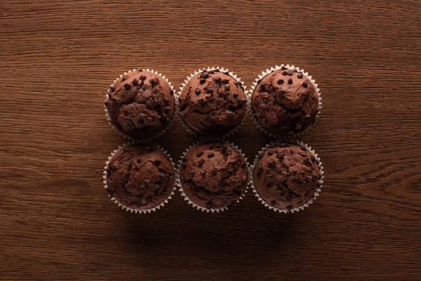 flat lay with fresh chocolate muffins on wooden surface - Foto, Bild