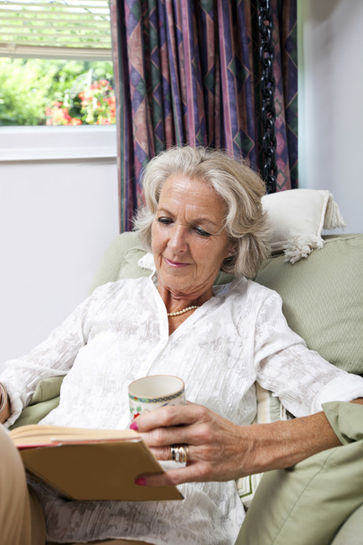 Senior woman with coffee cup reading book - Fotoğraf, Görsel