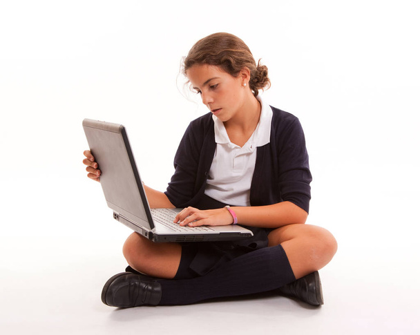 Schoolgirl sitting on the floor working with her laptop - Fotoğraf, Görsel