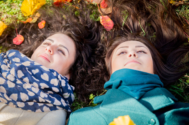 Girls lying on the grass in the autumn park - Foto, Imagen