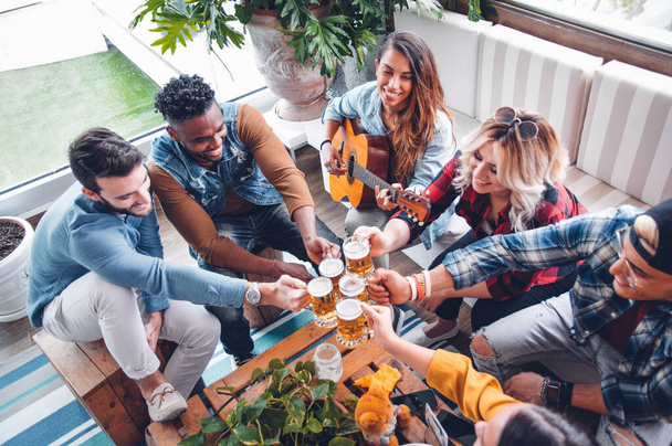 Group of mixed people having fun cheering home brew and playing  - Photo, Image