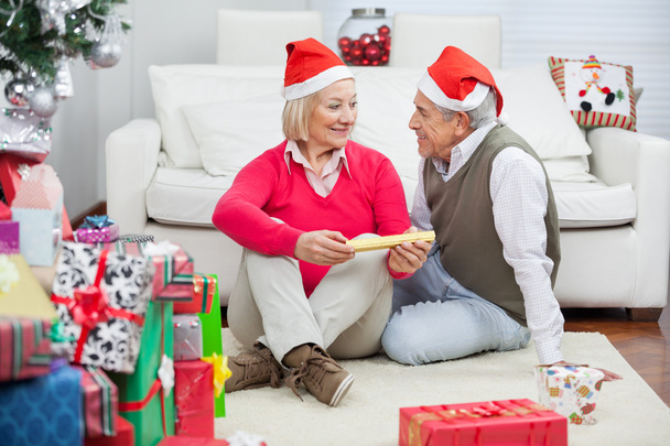 Couple Wearing Santa Hats Looking At Each Other - Foto, Imagen