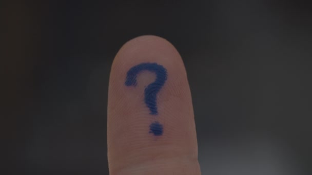 Human finger with written question mark on finger pad rising. Macro view of blue question mark on finger pad.  - Кадри, відео