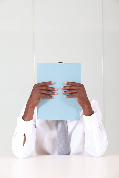 Businessman hiding behind blue document - Photo, image